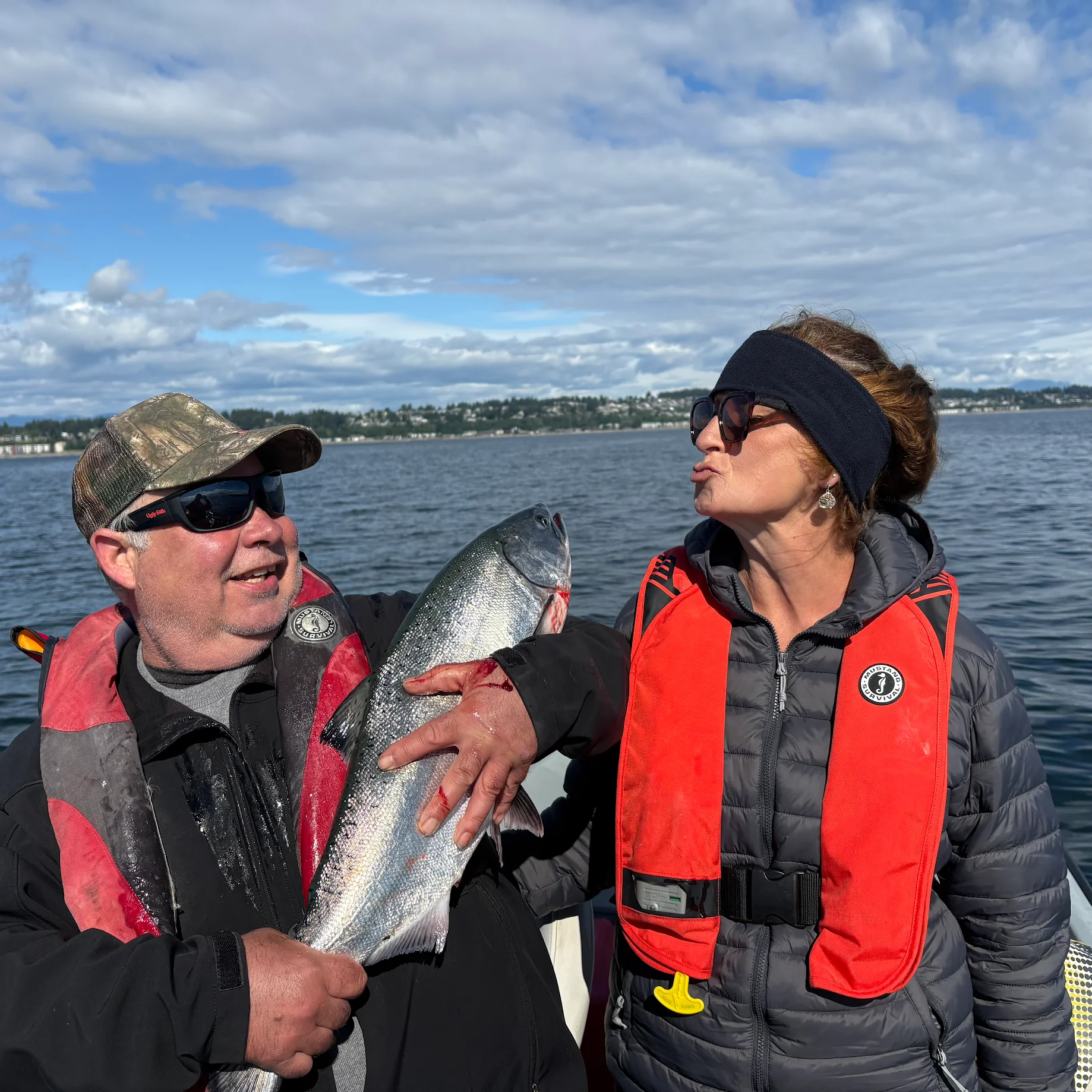 Couple sharing a celebratory kiss with their Chinook salmon catch on a Campbell River BC fishing charter