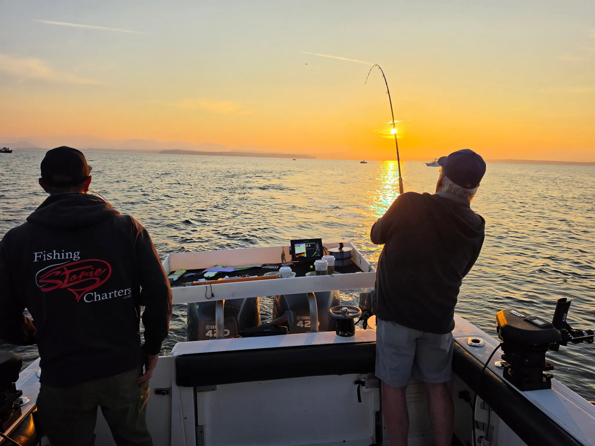 Anglers fighting a salmon at sunrise in Discovery Passage on a Fishing Storie Charters guided trip out of Campbell River BC