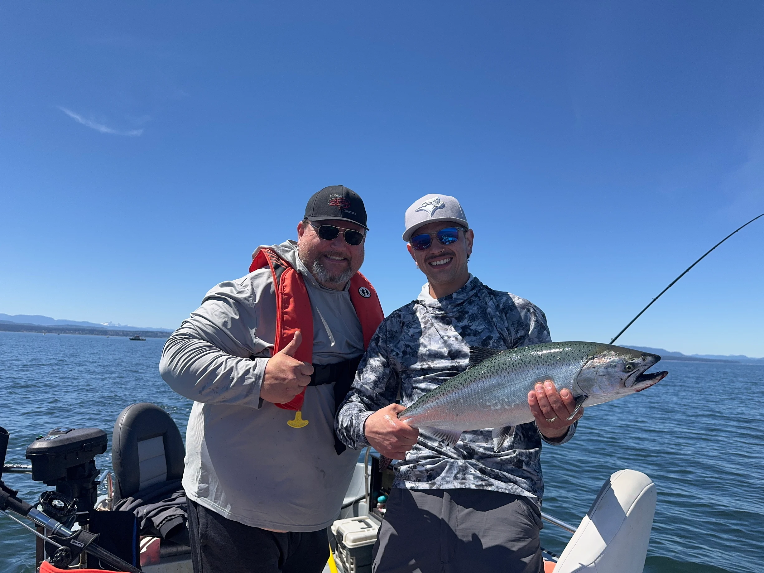 Two happy anglers showing off a trophy Chinook salmon on a bluebird day with Fishing Storie Charters in Campbell River BC