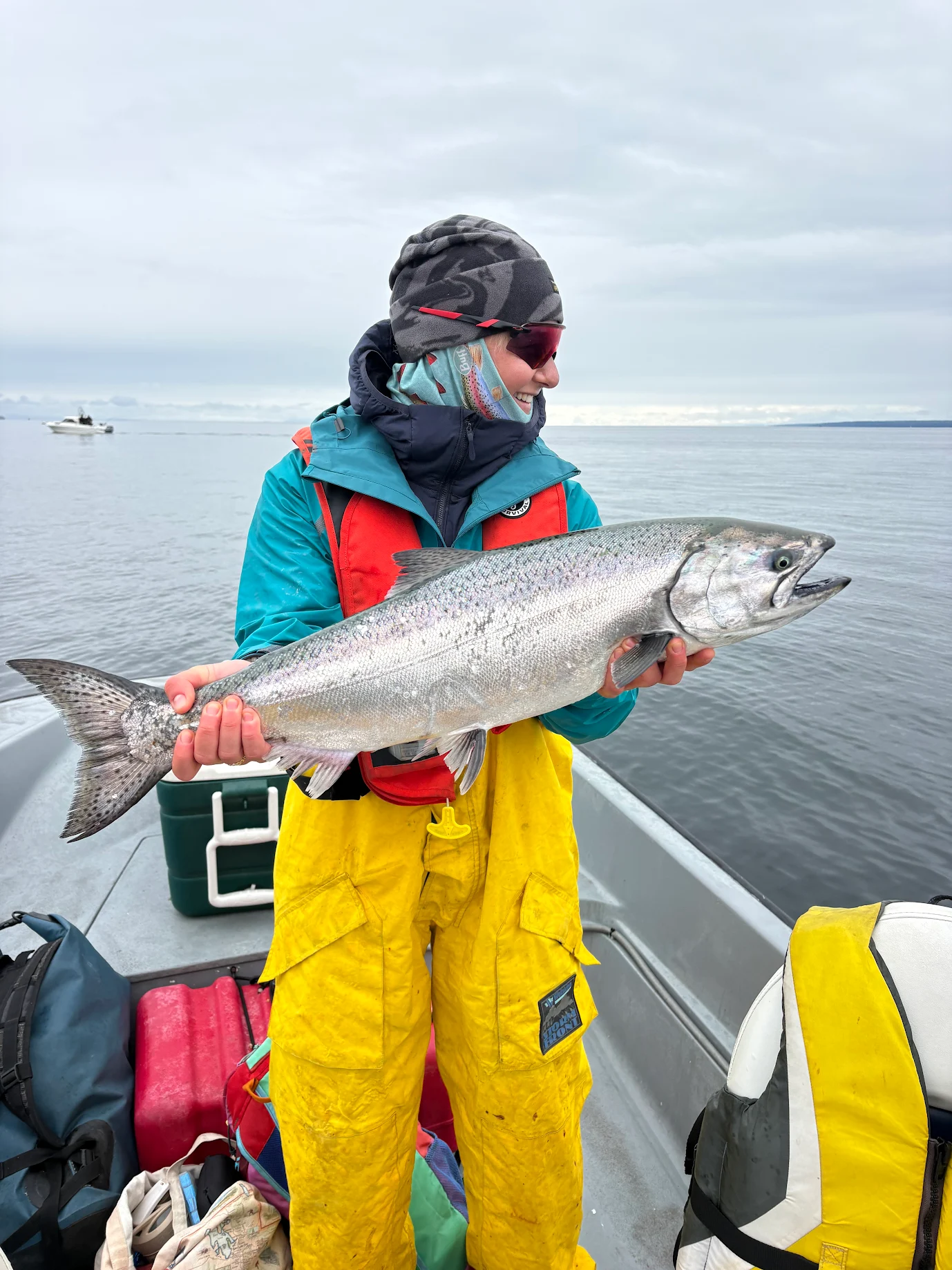 Female angler in yellow rain gear holding a bright Chinook salmon caught with Fishing Storie Charters Campbell River BC